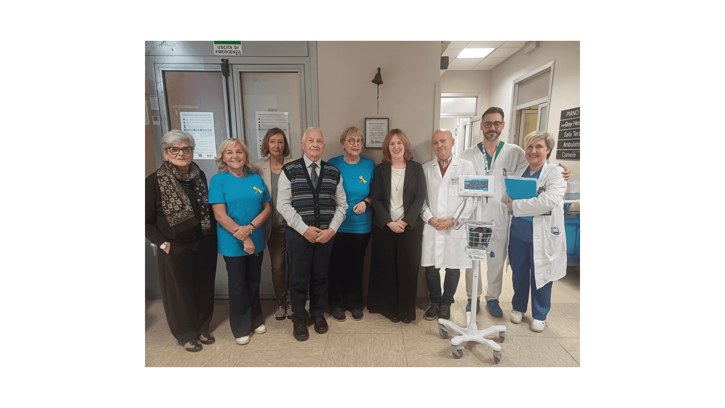 Foto di gruppo all’interno di un reparto ospedaliero, con volontari, rappresentanti dell’associazione e personale sanitario in posa accanto a un monitor multiparametrico su carrello.