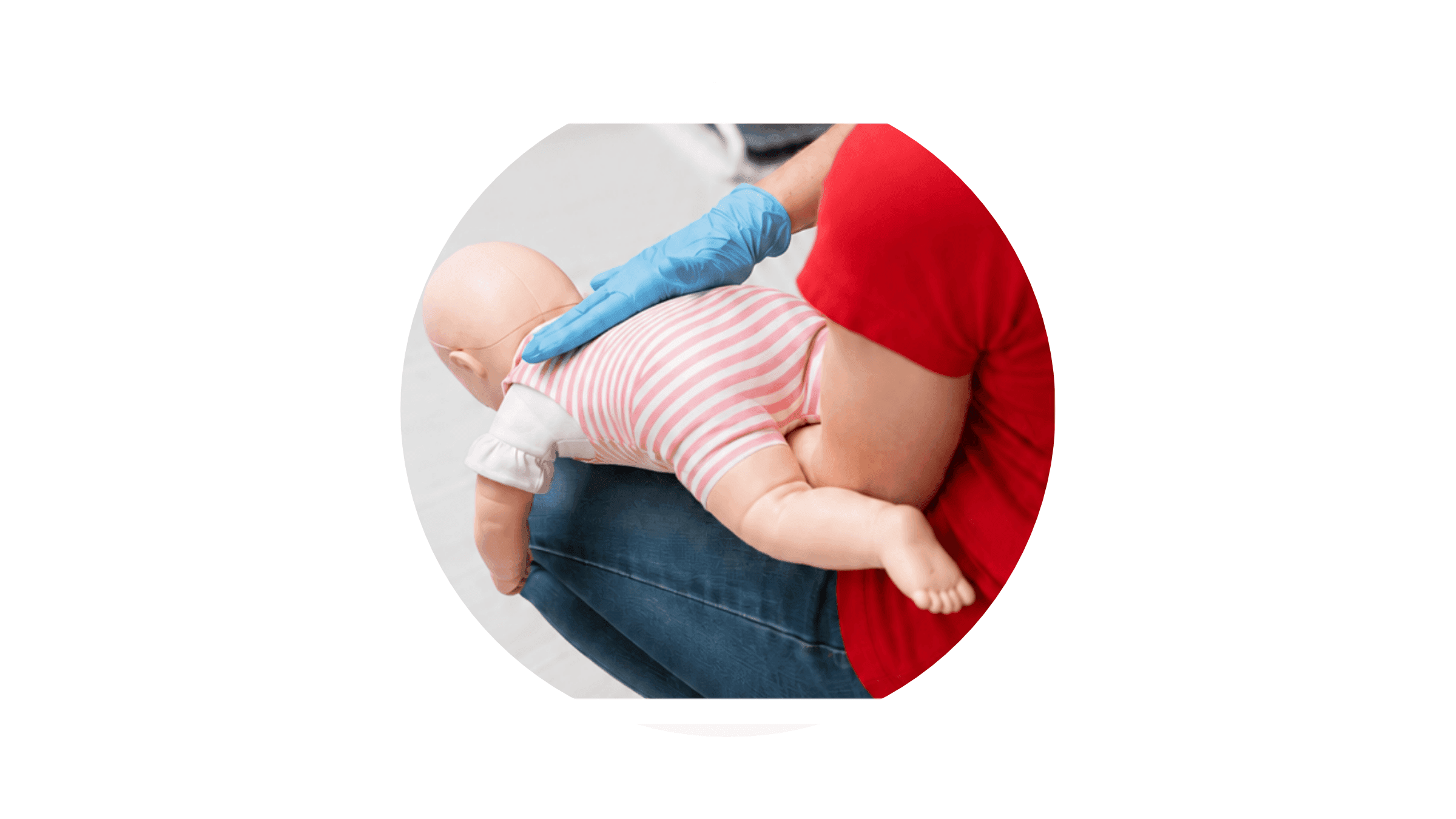 Persona che esegue una simulazione delle manovre di disostruzione pediatrica su un manichino di neonato, sostenendolo a pancia in giù e praticando colpi sulla schiena con una mano protetta da guanto.