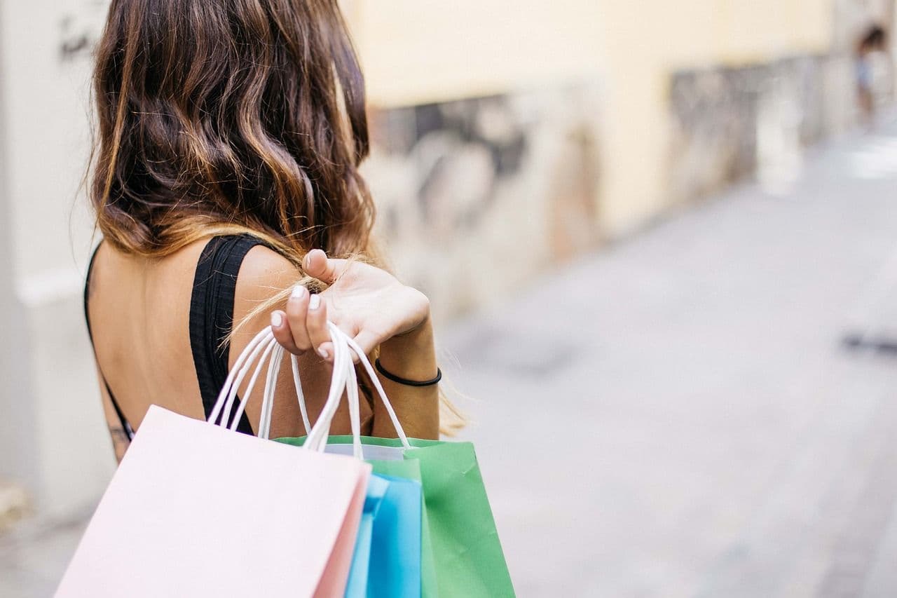 Donna di spalle con borse della spesa colorate in mano, in un contesto urbano, immagine utilizzata per rappresentare il welfare aziendale e le convenzioni dedicate ai dipendenti.